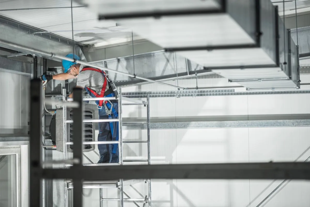 man installing a commercial heating unit inside a building