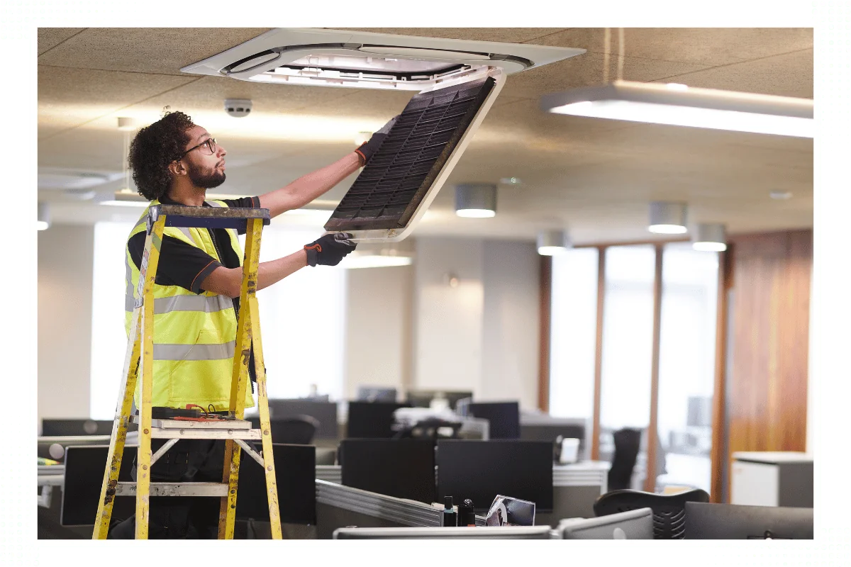 contractor repairing cooling unit in commercial office