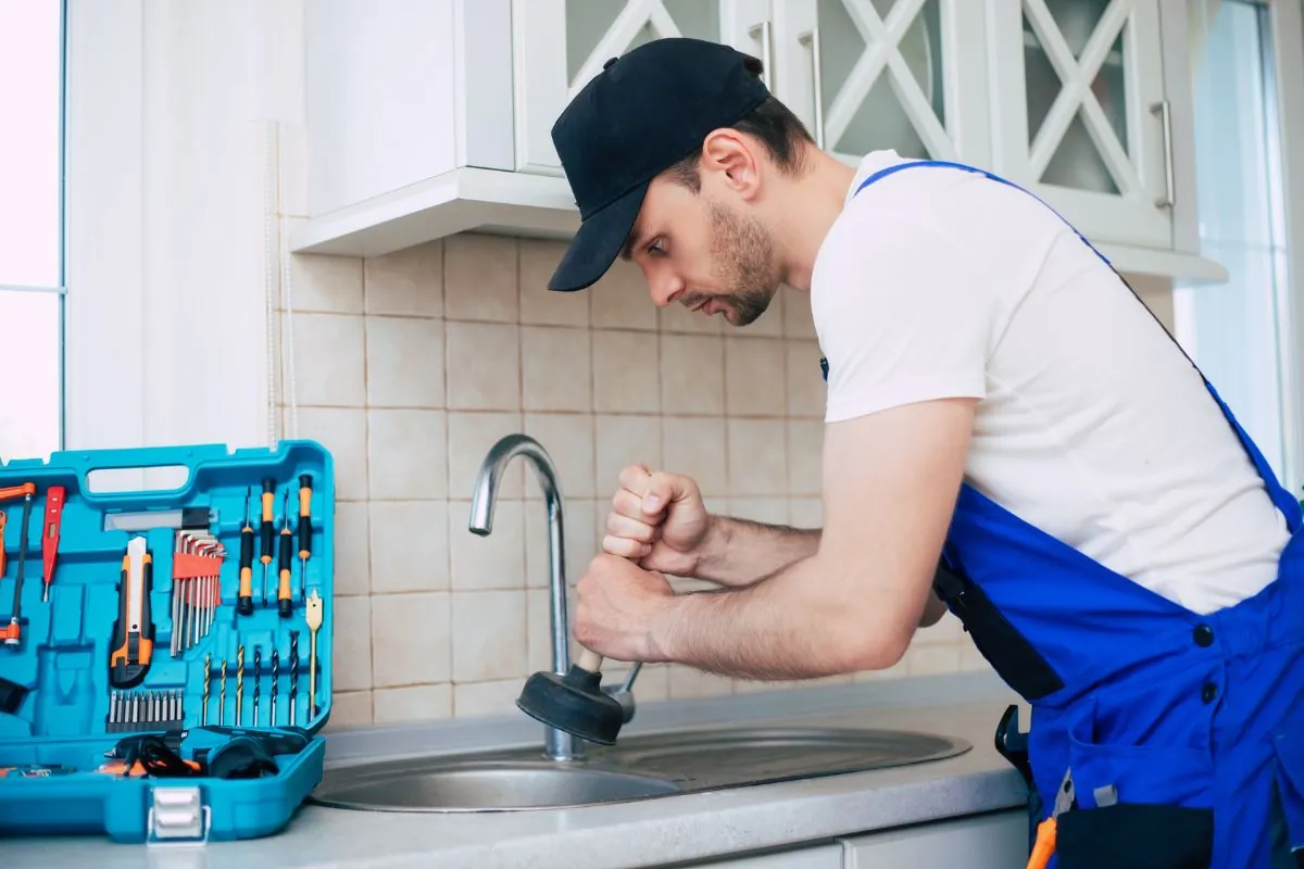 plumber cleaning clogged kitchen sink drainage