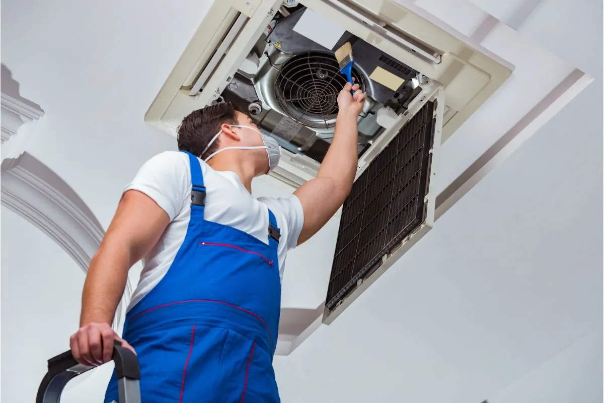 technician cleaning ceiling air conditioning unit