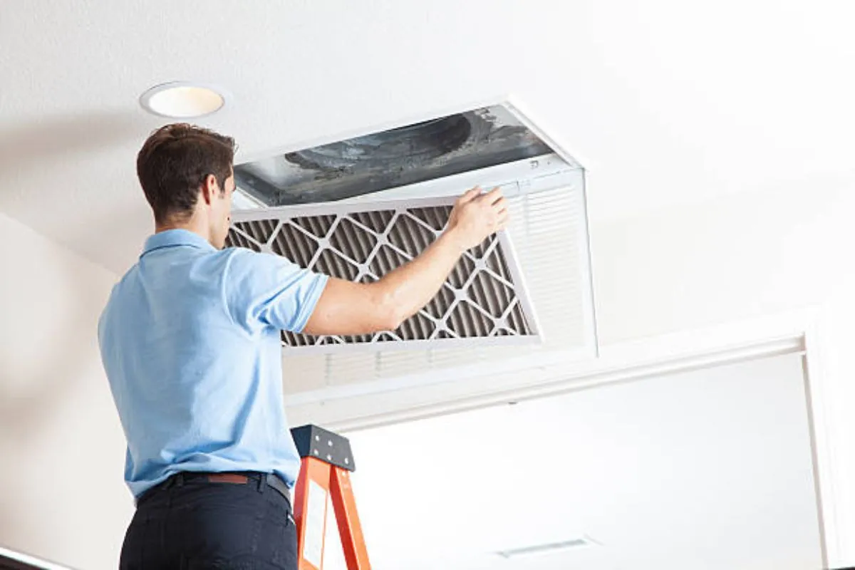 technician cleaning ventilation ceiling exhaust fan