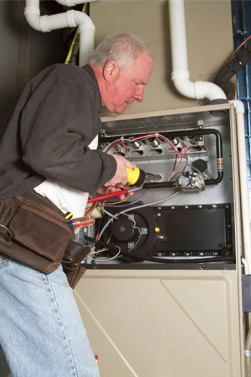 an old man is working on furnace maintenance.